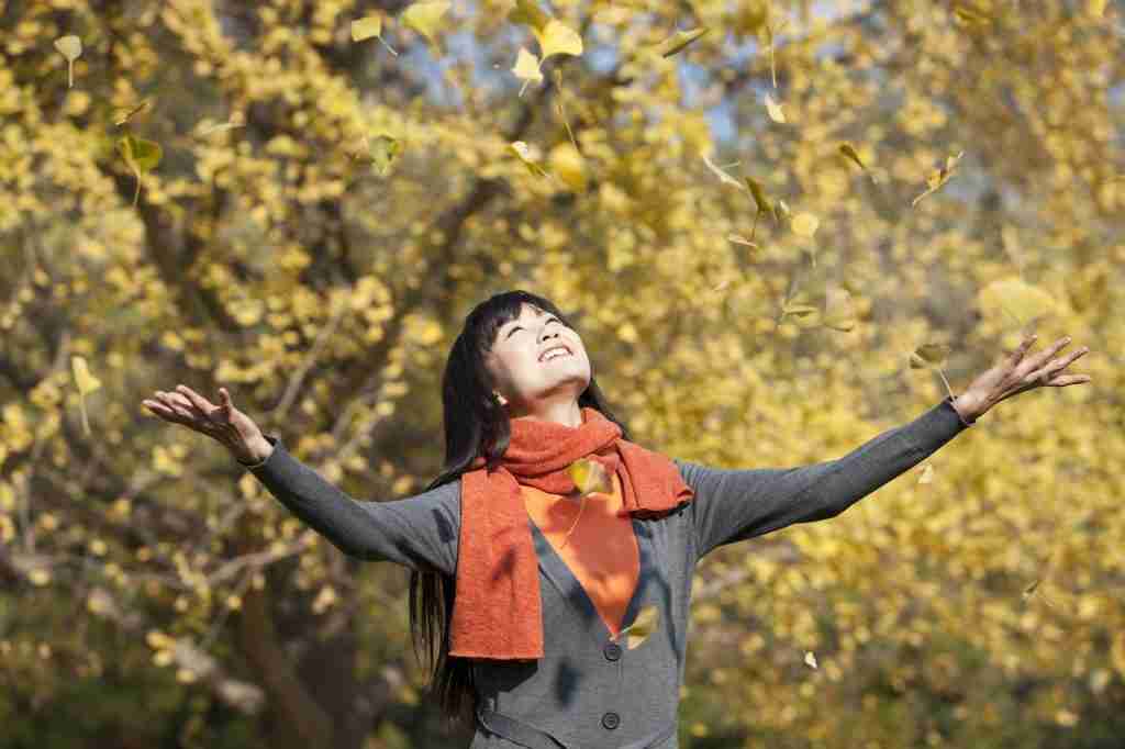 Happy young woman appreciating the golden autumn